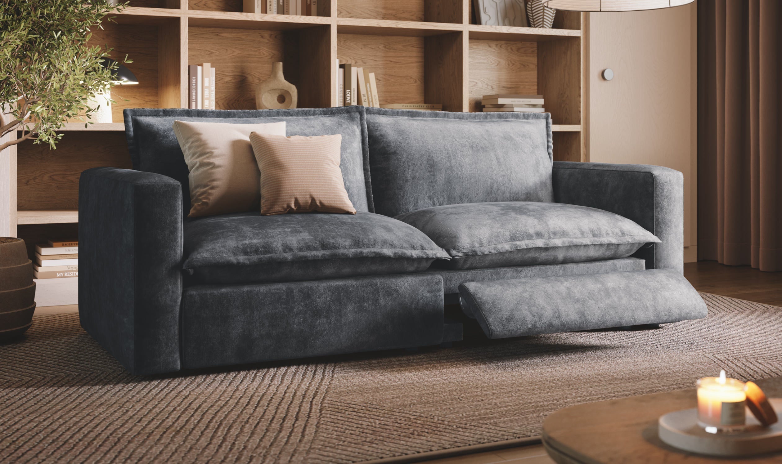 A stylish, dark gray reclining loveseat with one leg rest extended, situated in a warm, inviting room with wooden bookshelves